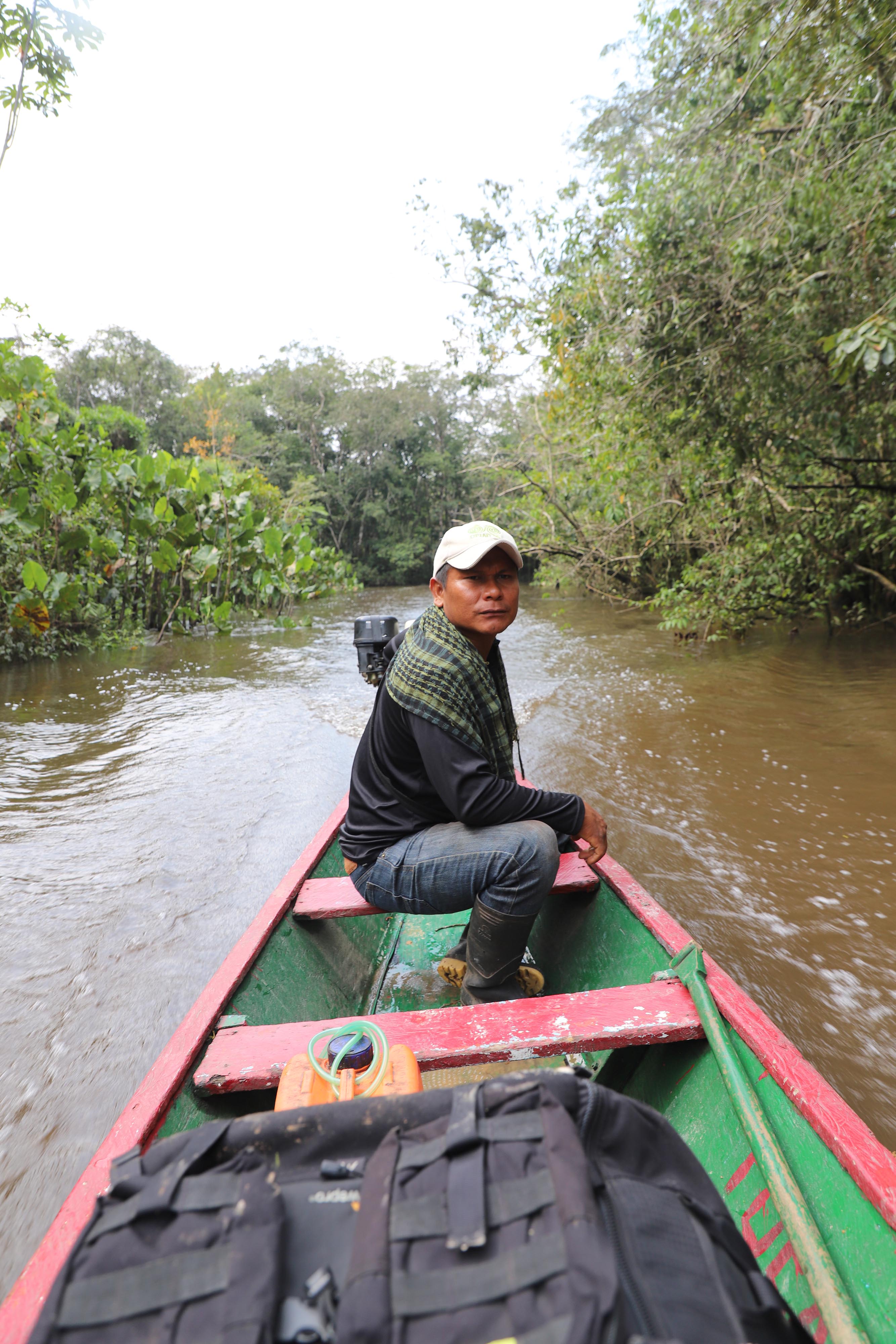 A man in a red and green canoe on a river.